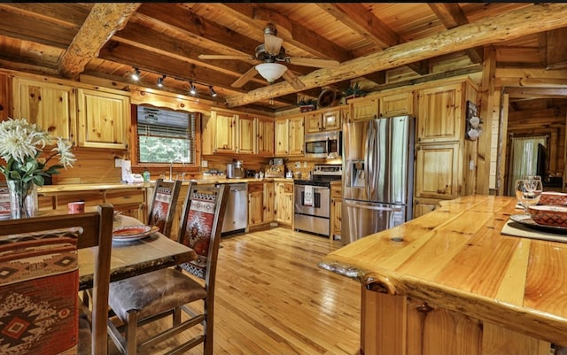 kitchen with wooden walls, wooden ceiling, stainless steel appliances, light wood-type flooring, and track lighting