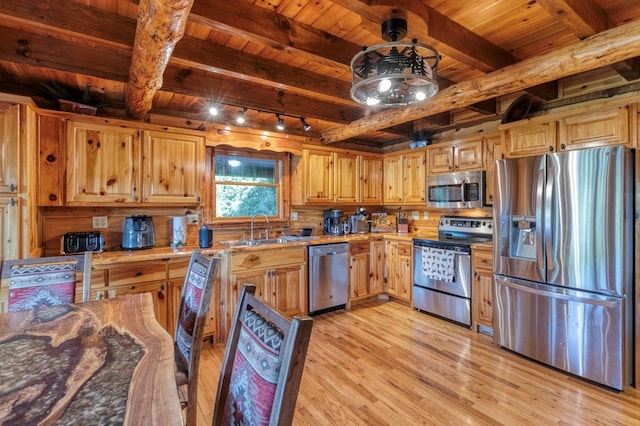 kitchen with rail lighting, appliances with stainless steel finishes, light wood-type flooring, light stone countertops, and sink