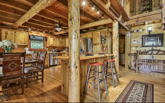 kitchen featuring track lighting, wood ceiling, stainless steel appliances, wooden walls, and beam ceiling