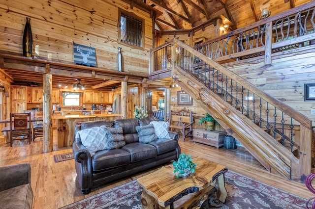 living room with beamed ceiling, wooden walls, light wood-type flooring, wood ceiling, and high vaulted ceiling