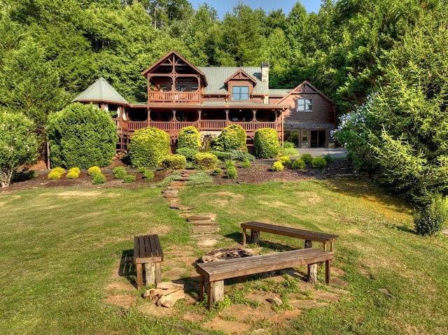 rear view of property featuring a wooden deck and a lawn