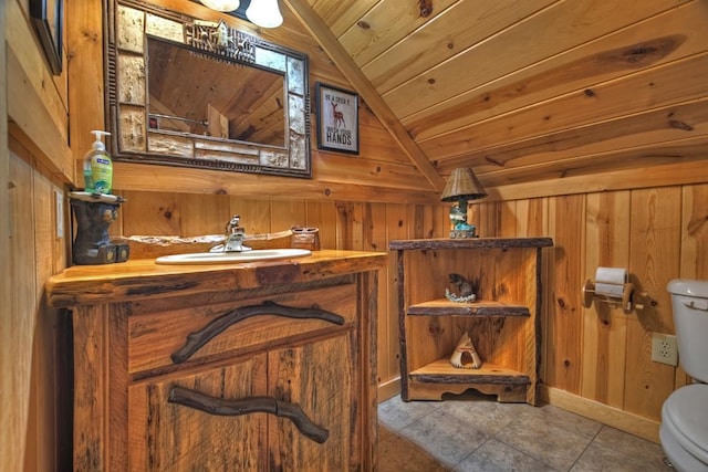 bathroom featuring vanity, toilet, wood walls, vaulted ceiling, and wooden ceiling