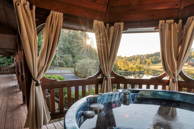 wooden terrace featuring a gazebo, a water view, and a hot tub