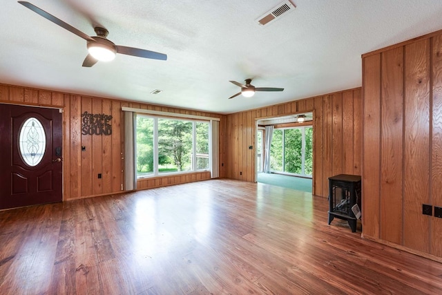 132 Silver Birch Ln, Marble, NC 28905 - unfurnished living room with ceiling fan, a wood stove, healthy amount of natural light, wood finished floors, and wooden walls