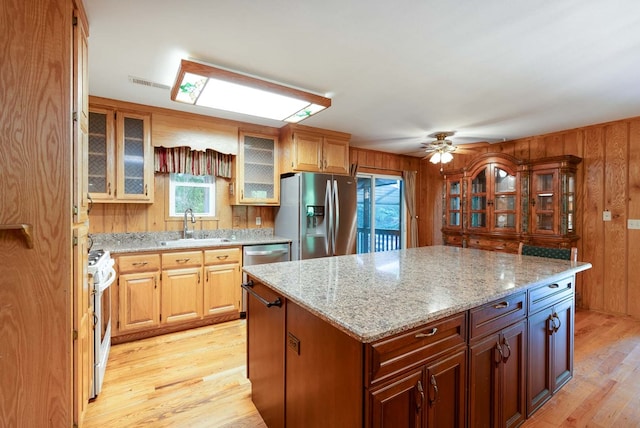 132 Silver Birch Ln, Marble, NC 28905 - kitchen featuring appliances with stainless steel finishes, light wood-style flooring, a kitchen island, light stone countertops, and wood walls