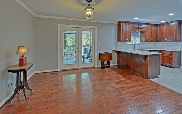 kitchen featuring a breakfast bar area, dark wood-type flooring, french doors, decorative backsplash, and kitchen peninsula