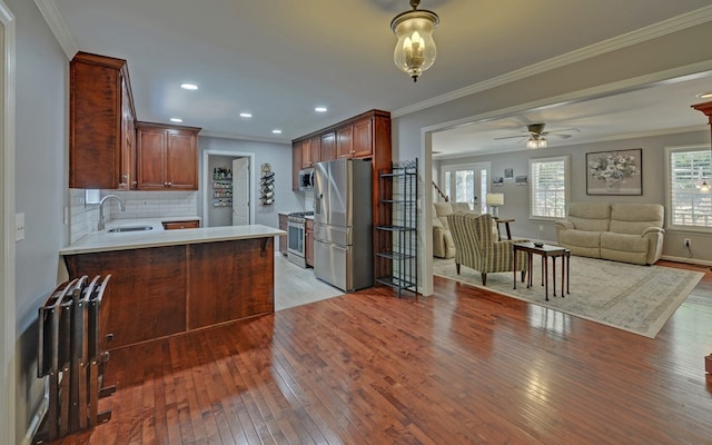 kitchen with sink, stainless steel appliances, tasteful backsplash, light hardwood / wood-style floors, and kitchen peninsula