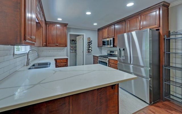 kitchen featuring sink, tasteful backsplash, light wood-type flooring, appliances with stainless steel finishes, and kitchen peninsula