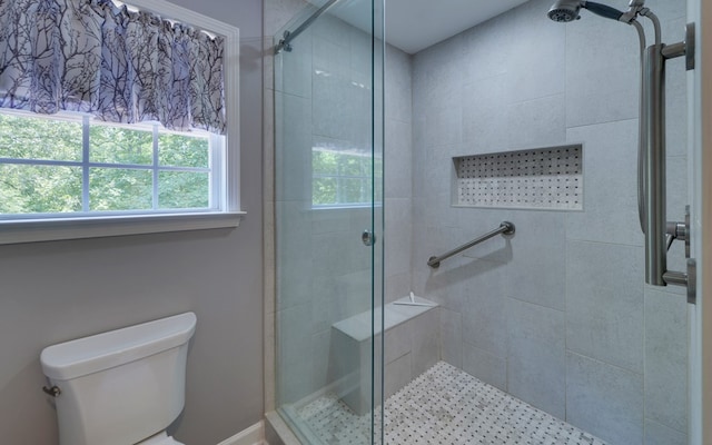 bathroom featuring a shower with door and toilet