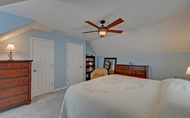 bedroom featuring vaulted ceiling, light colored carpet, ceiling fan, and a textured ceiling