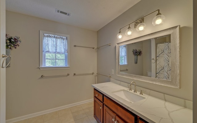 bathroom with plenty of natural light, tile patterned flooring, vanity, and a textured ceiling