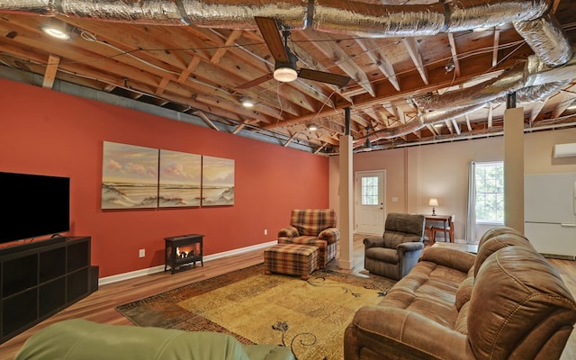 living room featuring hardwood / wood-style flooring, a wood stove, and ceiling fan