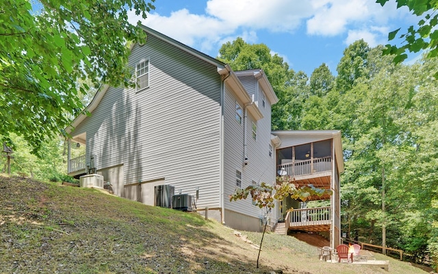 view of property exterior with a sunroom and central air condition unit