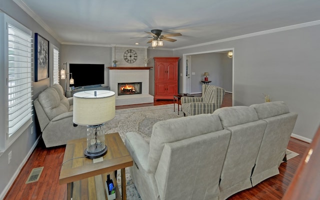 living room featuring crown molding, ceiling fan, dark hardwood / wood-style flooring, and a brick fireplace