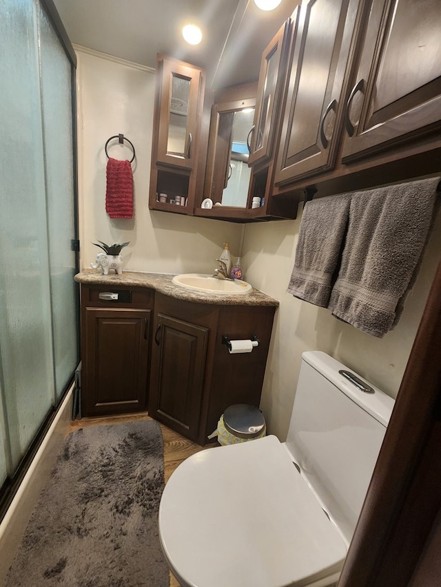 full bathroom with a shower with shower door, vanity, and toilet