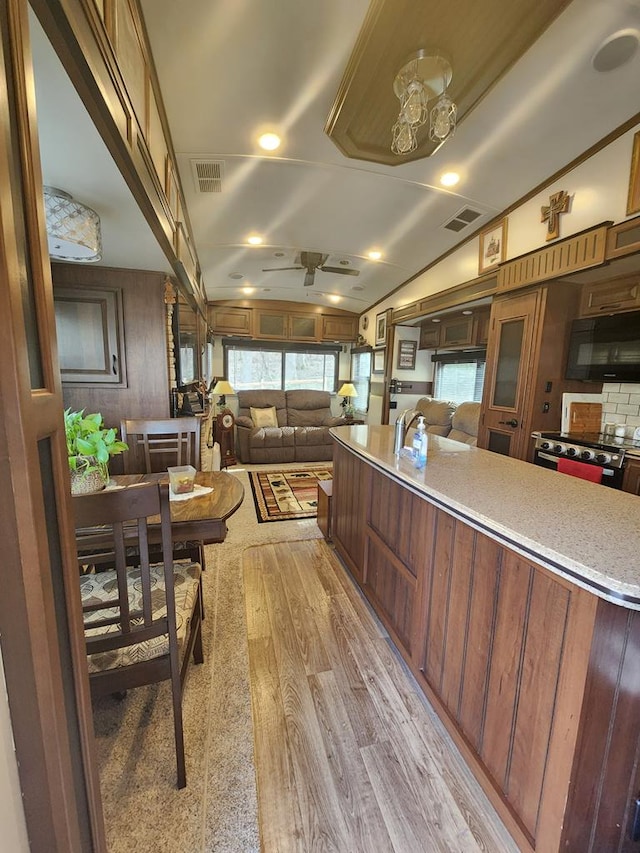 kitchen with black microwave, lofted ceiling, visible vents, and light wood-style floors