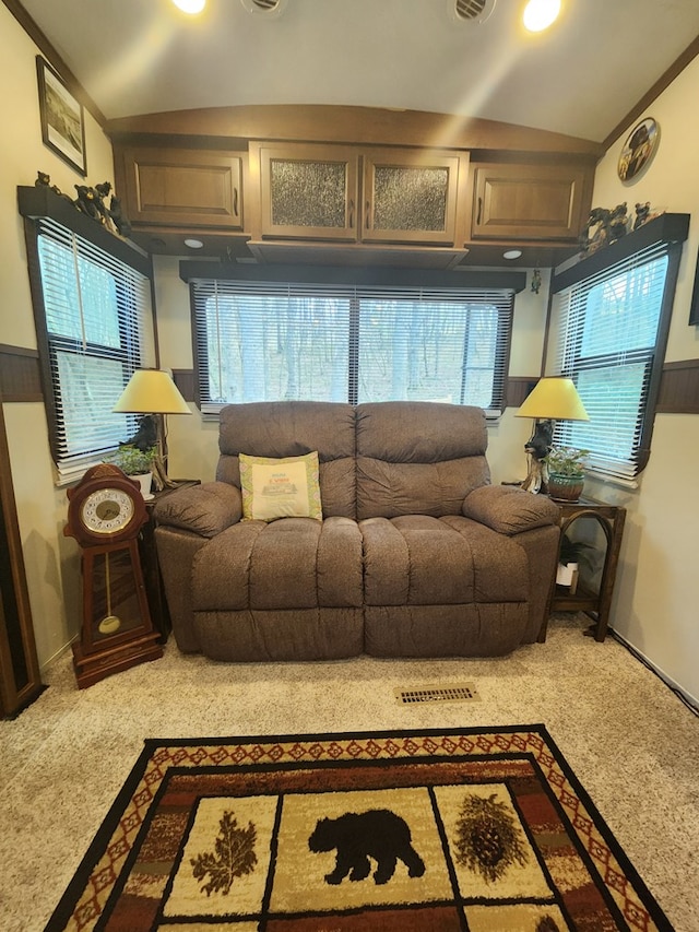 living area featuring lofted ceiling, a wainscoted wall, and visible vents