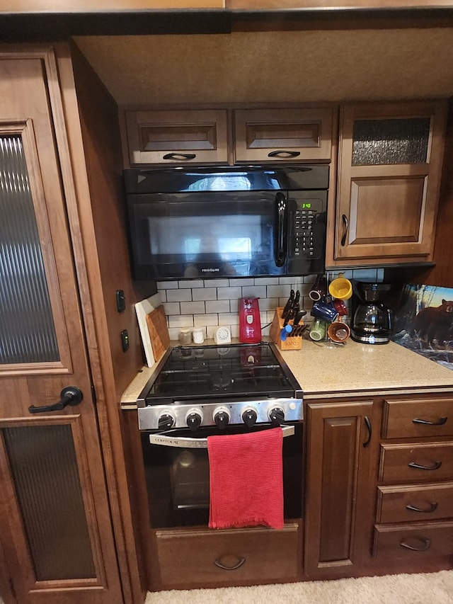 kitchen with black microwave, decorative backsplash, electric stove, and light countertops