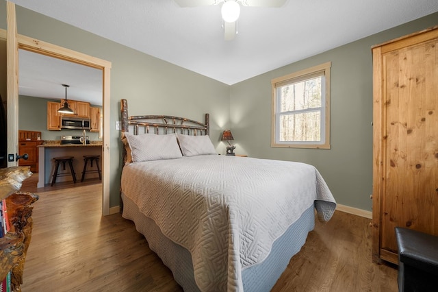 bedroom with a ceiling fan, wood finished floors, and baseboards