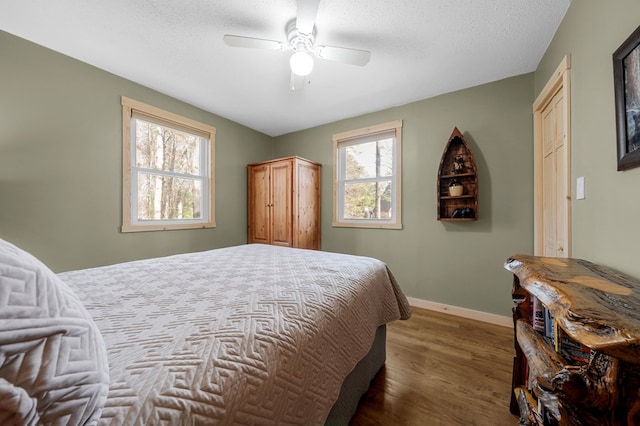 bedroom featuring ceiling fan, baseboards, a textured ceiling, and wood finished floors