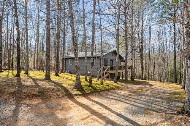 view of front facade featuring a wooden deck, stairs, and gravel driveway