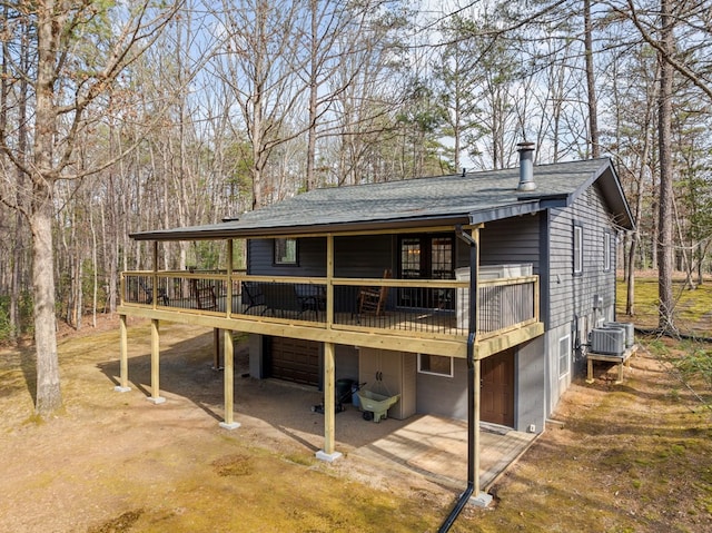 back of house with a garage, a shingled roof, and a deck