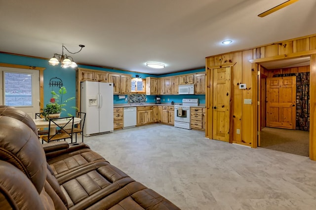 kitchen with light carpet, white appliances, ceiling fan with notable chandelier, wooden walls, and pendant lighting