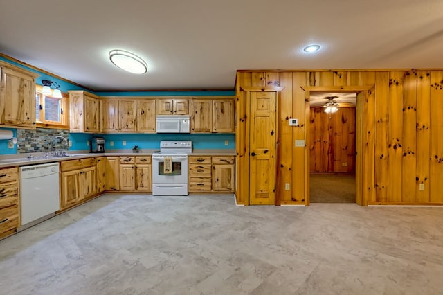 kitchen featuring ceiling fan, sink, backsplash, wood walls, and white appliances