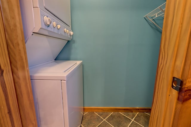 laundry area featuring dark tile patterned flooring and stacked washer and dryer