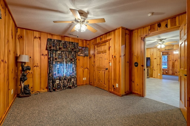 unfurnished room with carpet, ceiling fan, a textured ceiling, and wooden walls