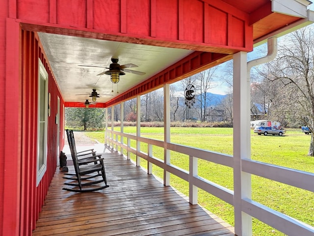 deck with ceiling fan, a porch, and a yard