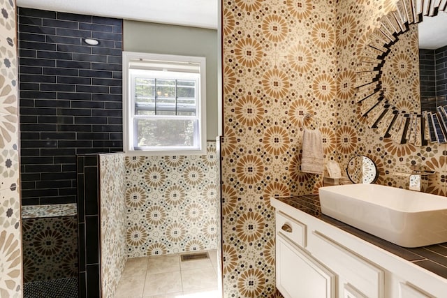 full bathroom with visible vents, tile patterned floors, vanity, a walk in shower, and tile walls