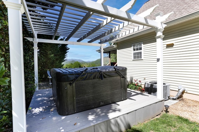 wooden deck featuring a hot tub and a pergola