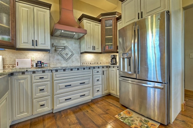 kitchen featuring dark wood-style floors, custom range hood, decorative backsplash, and stainless steel fridge with ice dispenser