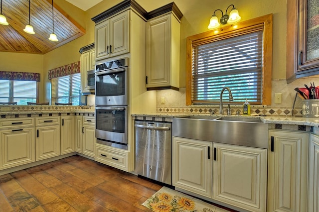 kitchen with a sink, appliances with stainless steel finishes, dark wood finished floors, and cream cabinetry