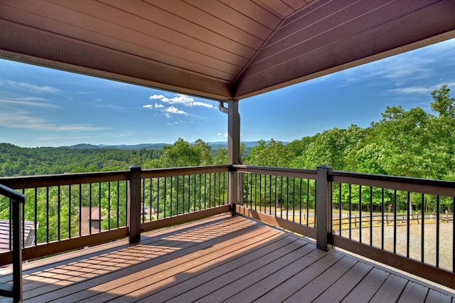 wooden deck with a forest view and a mountain view