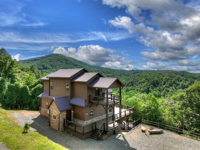 exterior space with stone siding, metal roof, a view of trees, and gravel driveway