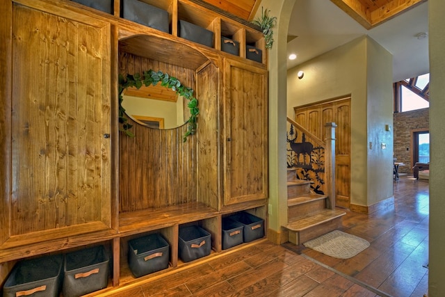 mudroom with wood-type flooring, a towering ceiling, and baseboards