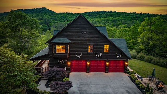 view of front of property with a wooded view and concrete driveway
