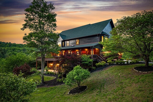 back of property featuring a lawn, a shingled roof, and covered porch