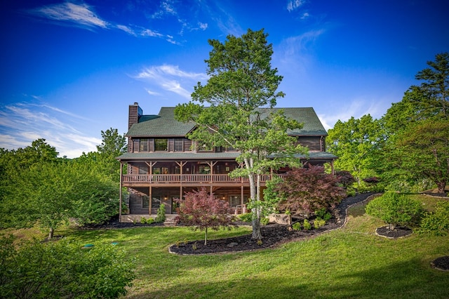 back of property featuring a chimney, a lawn, and a shingled roof