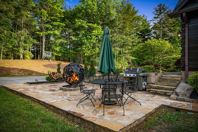 view of patio featuring grilling area, outdoor dining area, and view of scattered trees