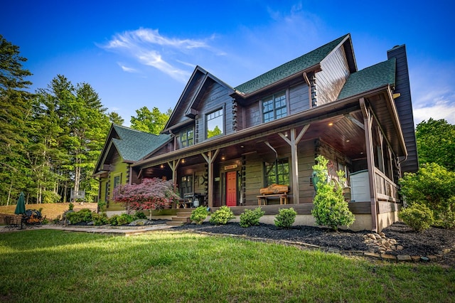 view of front facade featuring covered porch, a chimney, a front lawn, and roof with shingles