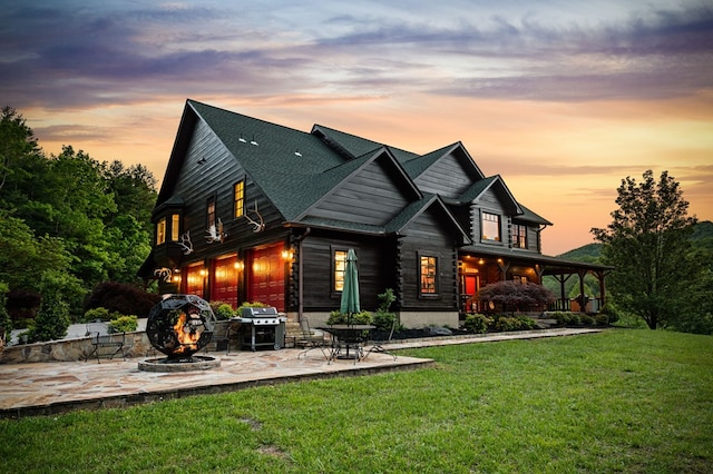 rear view of property featuring a patio, a lawn, and roof with shingles