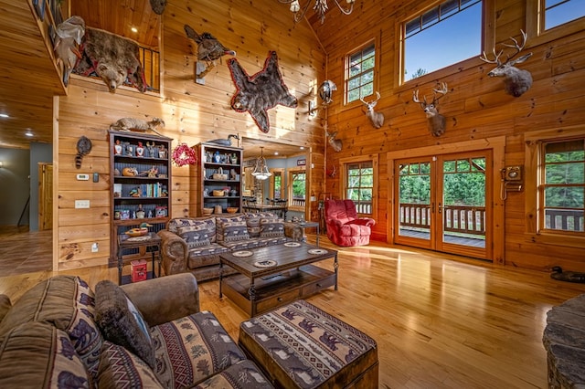 living room featuring a chandelier, a high ceiling, wood walls, and wood finished floors