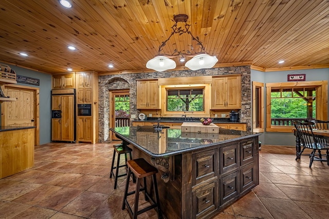 kitchen with paneled built in refrigerator, plenty of natural light, a sink, recessed lighting, and a kitchen breakfast bar