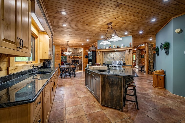 kitchen featuring a sink, wooden ceiling, a kitchen bar, a large fireplace, and recessed lighting