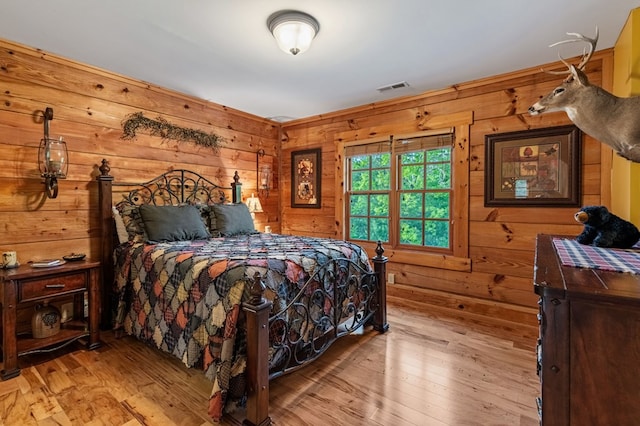 bedroom featuring wooden walls and hardwood / wood-style floors