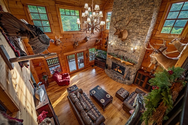living room featuring a chandelier, wood finished floors, a fireplace, wooden walls, and lofted ceiling