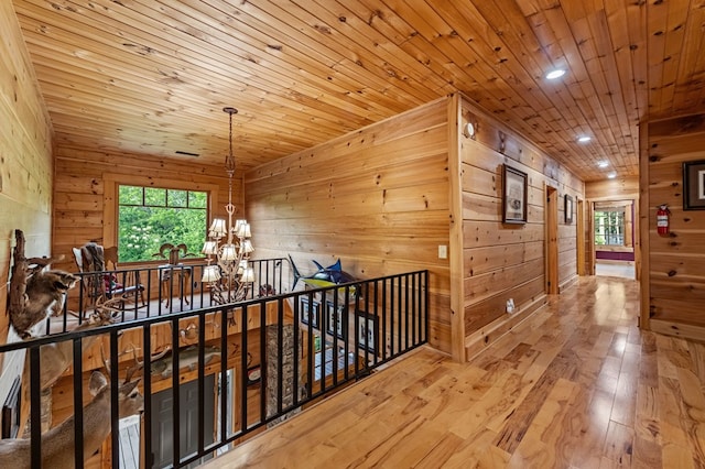 hall featuring a chandelier, wood walls, wood ceiling, and wood-type flooring